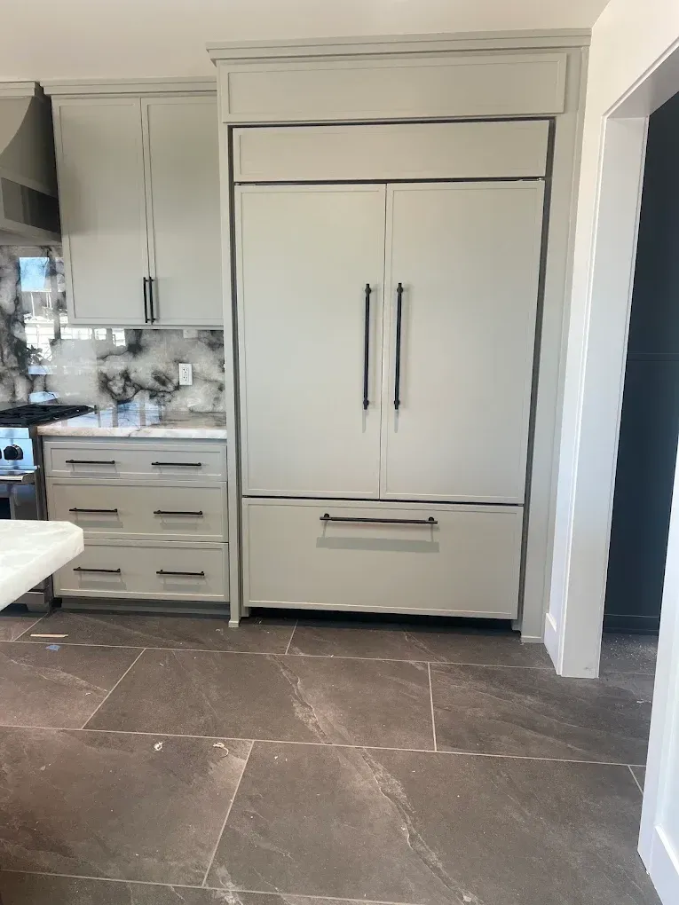 Modern kitchen with a large built-in stainless steel refrigerator and gray cabinets, viewed from the floor level