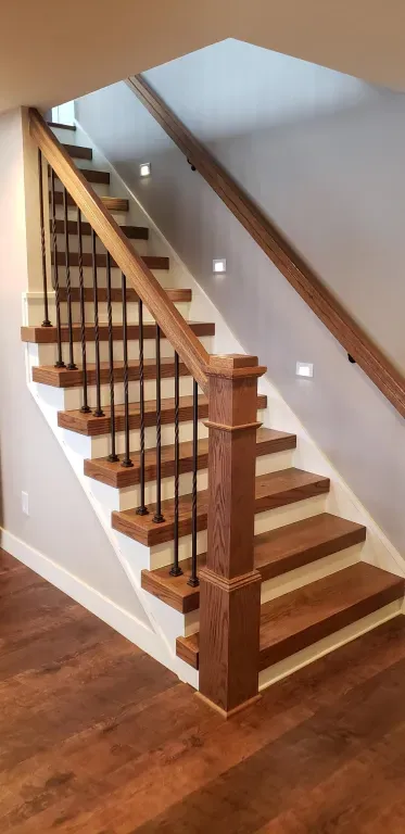 A wooden staircase with a metal railing in a house.