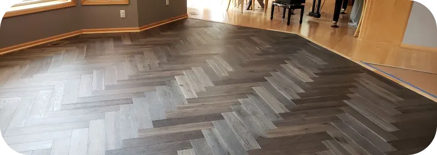 A wooden floor with a herringbone pattern in a room.