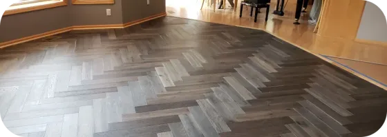 A wooden floor with a herringbone pattern in a room.