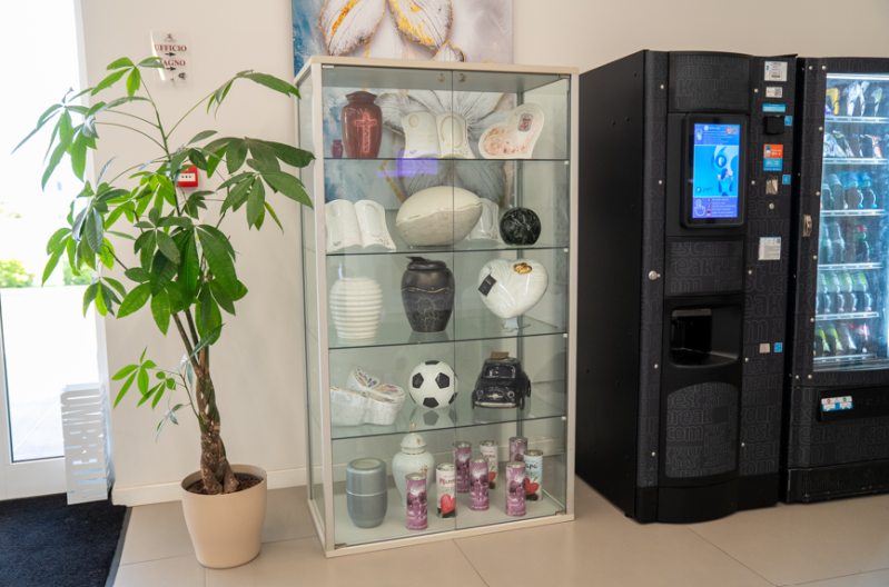 Atrio dell'ufficio con pianta in vaso, vetrina con ciotole e distributori automatici.