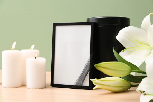 Natura morta in una spa con candele bianche, cornice nera e gigli bianchi su una superficie di legno chiaro.