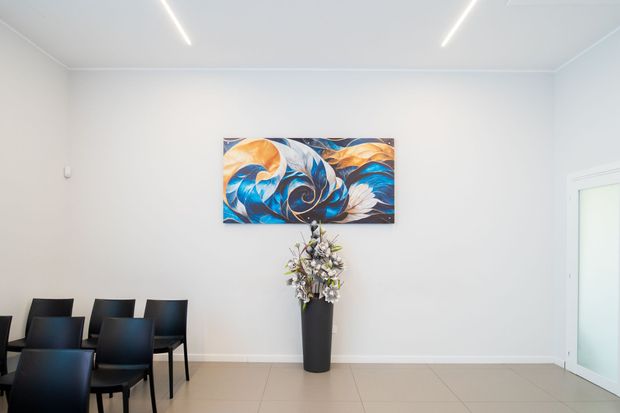 Luminosa sala riunioni moderna con sedie e tavoli neri, ampie finestre e un murale.