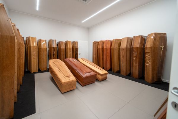 In una stanza luminosa, file di bare di legno, con tre bare chiuse al centro.
