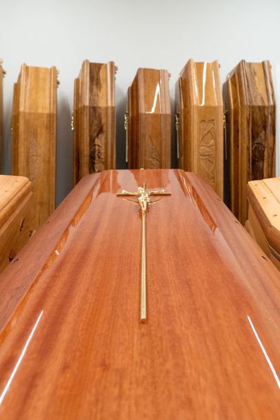 Bara di legno con crocifisso d'oro in una chiesa o in un ambiente funebre.