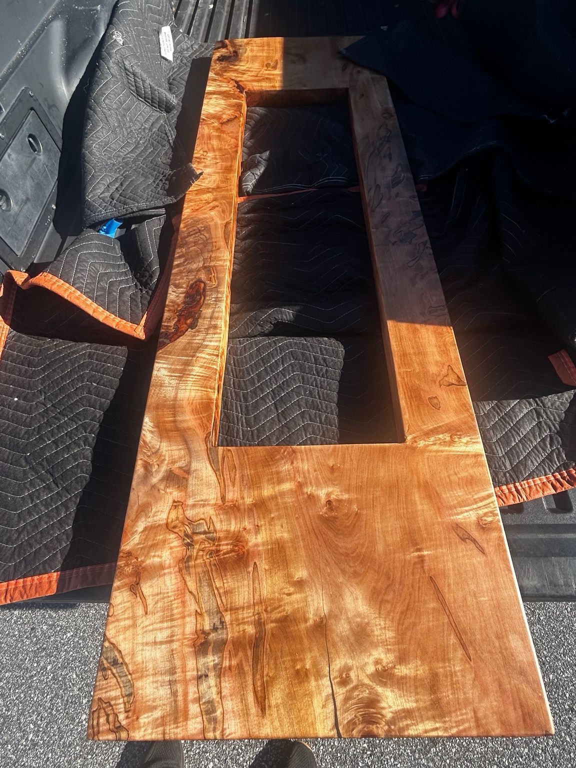 Wooden board with a rectangular cutout, resting on a black textured seat with orange trim.