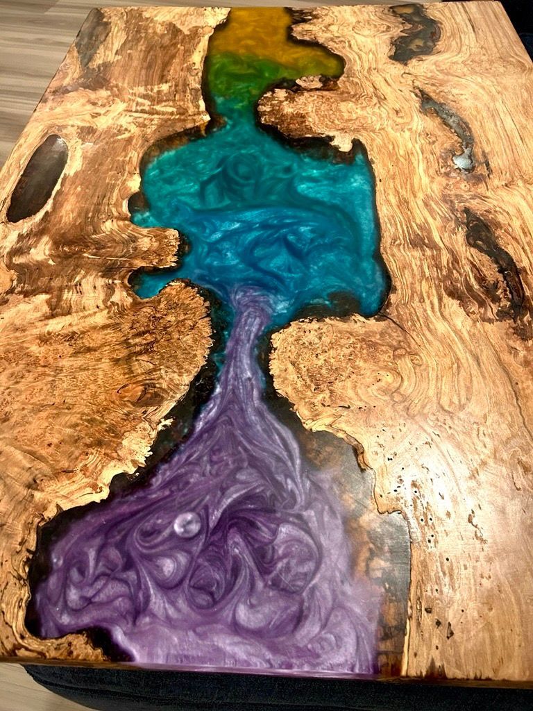 Wooden table with a river of layered, swirling blue, green, and purple resin.