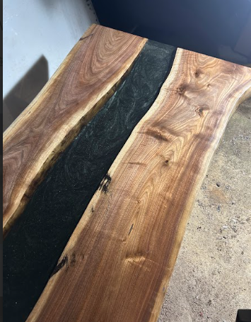 Wooden table with a dark-colored resin river in the center.