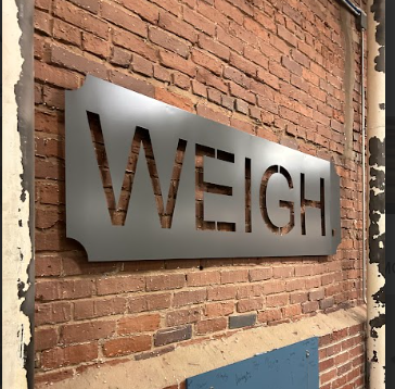 A metal sign on a brick wall reads