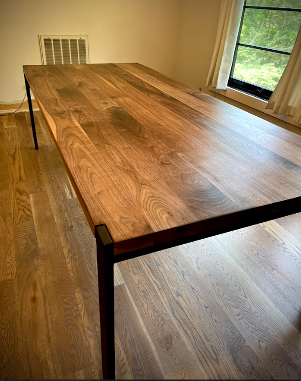 A wooden table is sitting in a room next to a window.