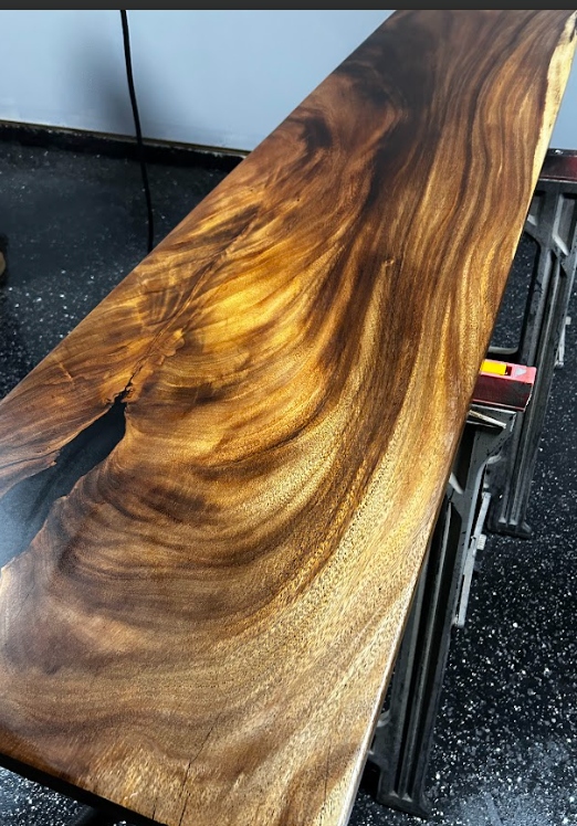 Wooden slab with swirling grain in dark brown and gold tones.