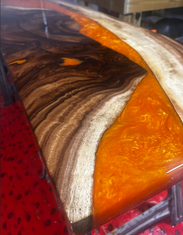 Close-up of a glossy abstract resin surface with orange, brown, white, and red swirls.