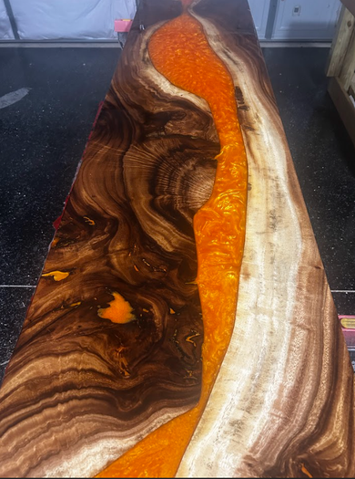 Decorative wood slab with natural grain and a bright orange resin inlay on a dark countertop