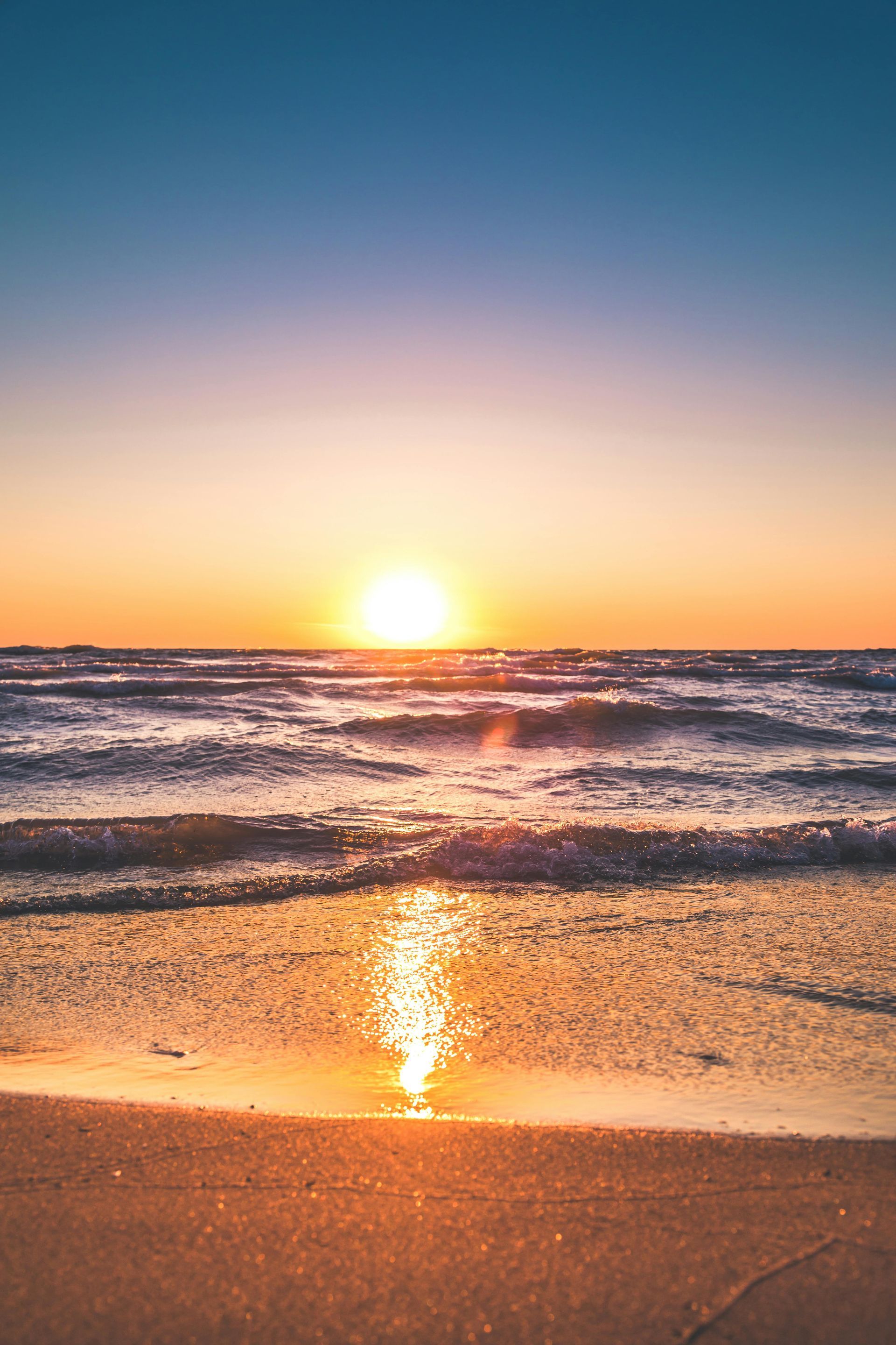 The sun is setting over the ocean on a beach.