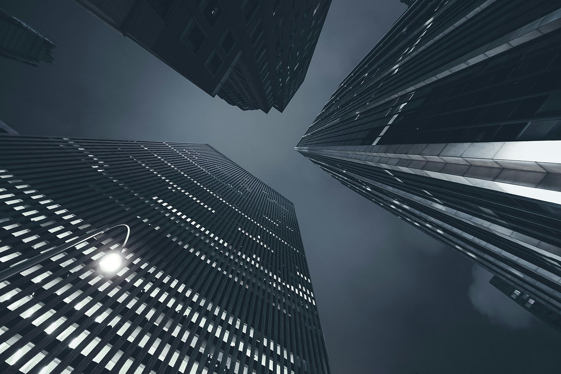 Looking up at a city skyline at night with a street light in the foreground