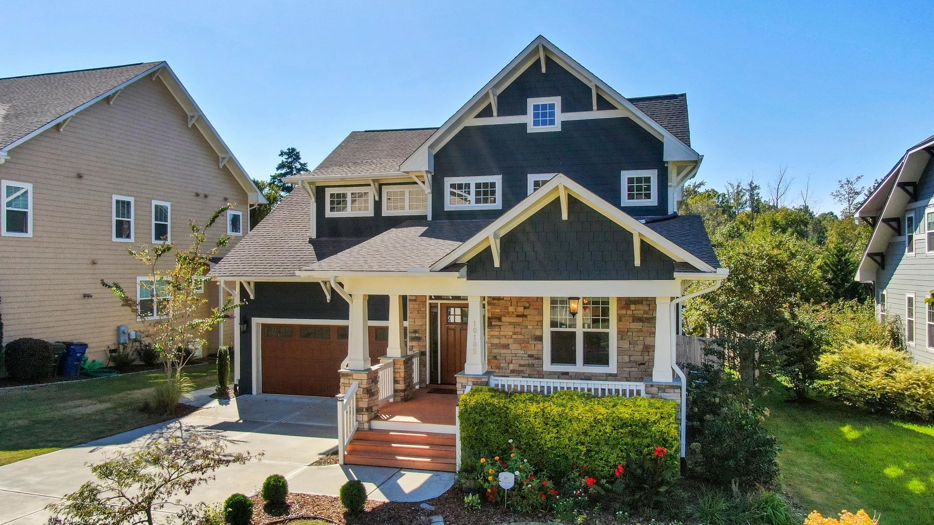 A large house with a porch and a garage is surrounded by other houses in Raleigh, NC
