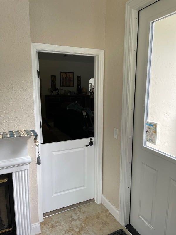 Interior hallway with two white doors, one open to a dim room and one glass-panel exterior door.