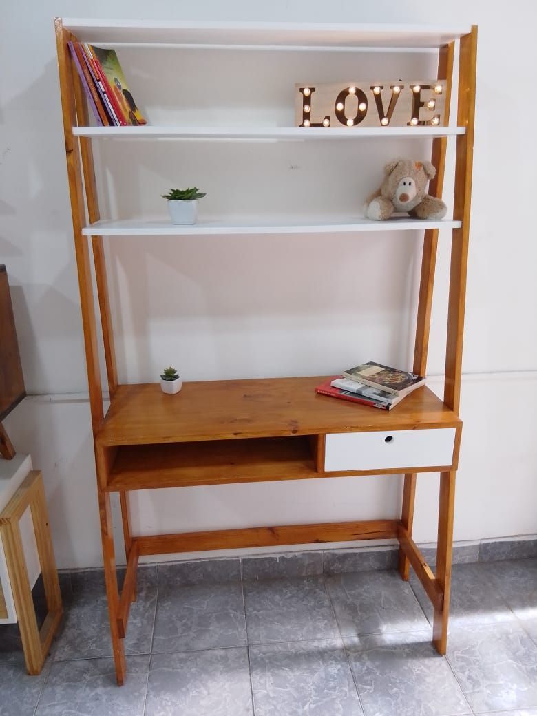 Escritorio de madera con estantes, que contiene libros, una planta, un osito de peluche y un cartel iluminado que dice 