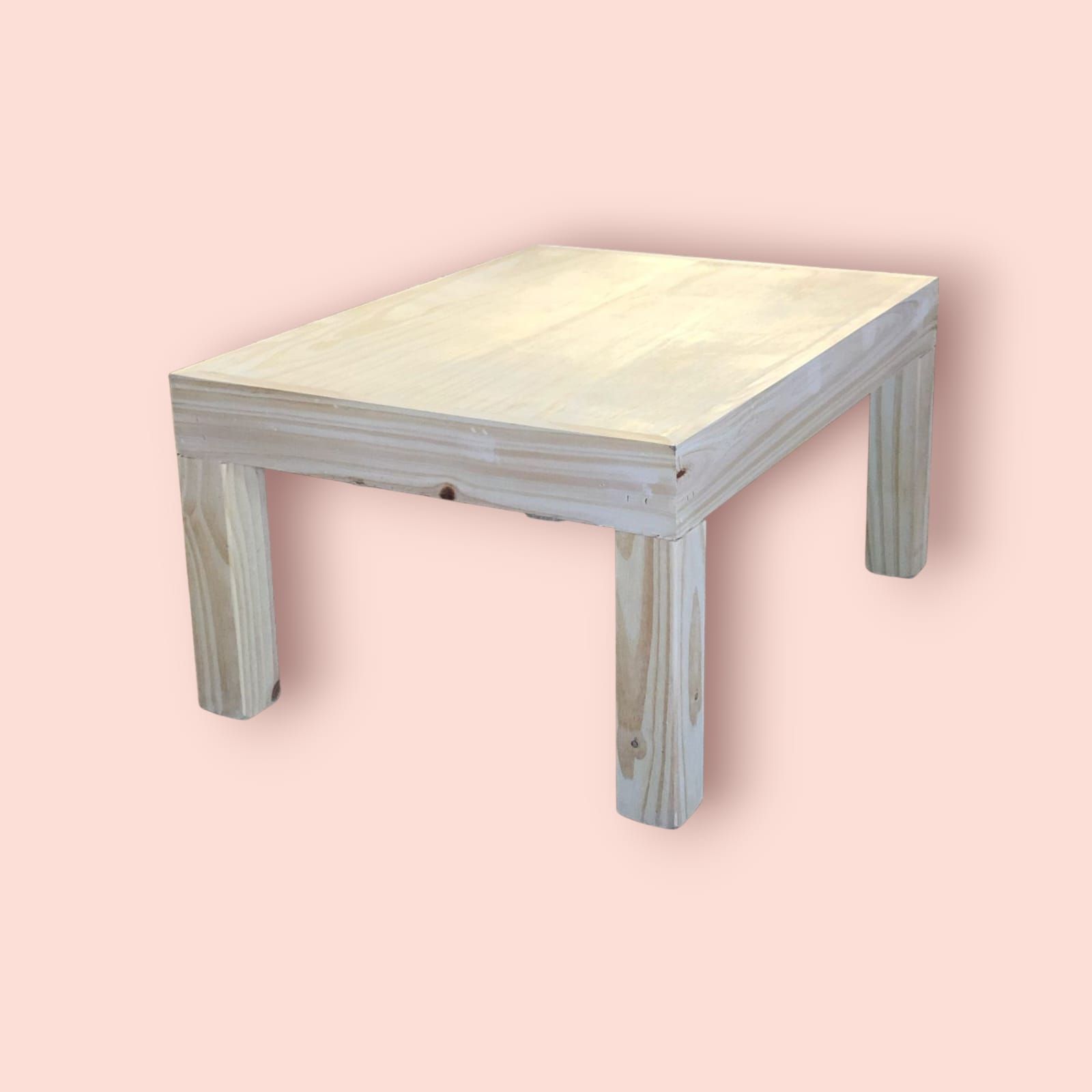 Mesa rectangular de madera con cuatro patas cuadradas, sobre fondo rosa.