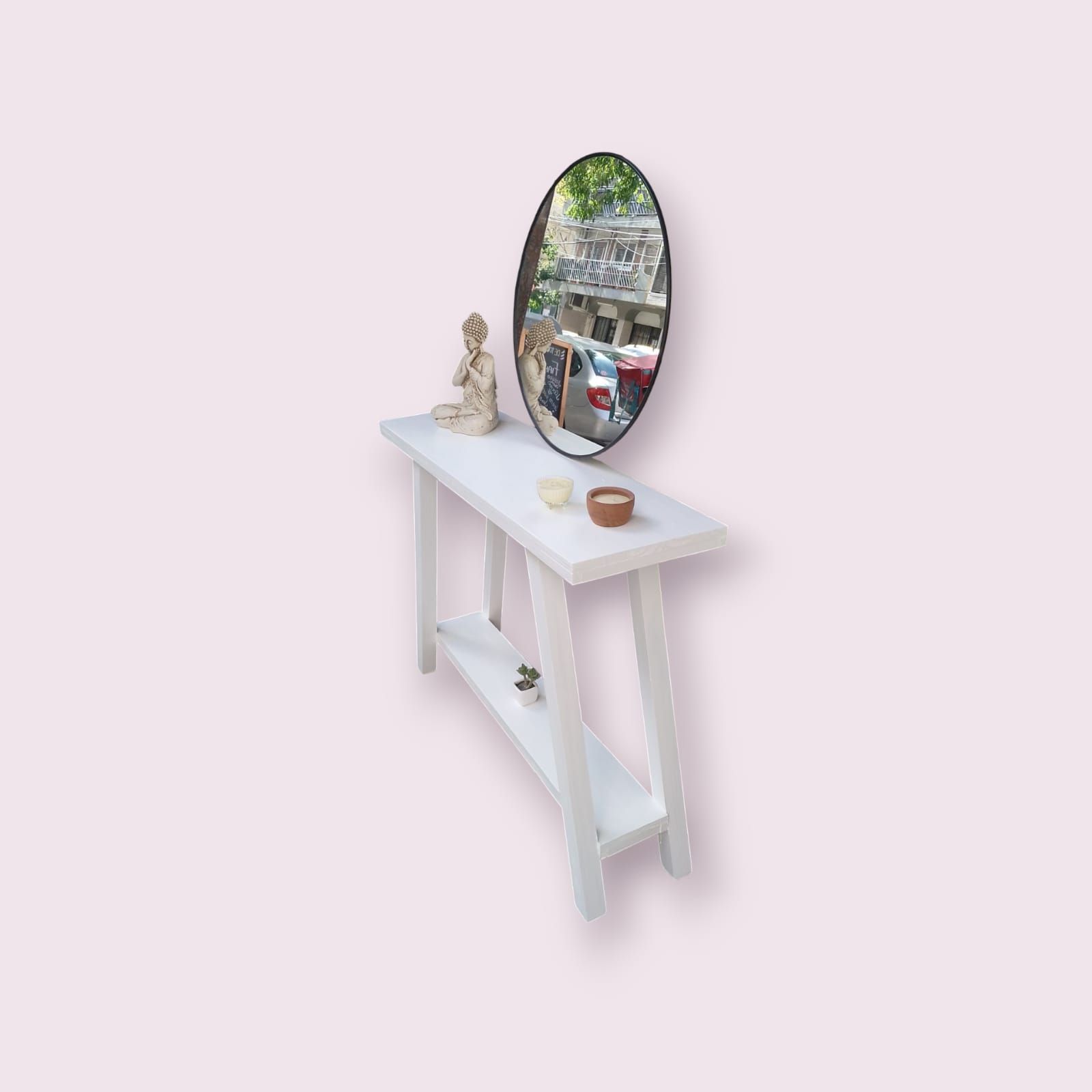 Consola blanca con espejo que refleja árboles, una pequeña estatua y jabón.
