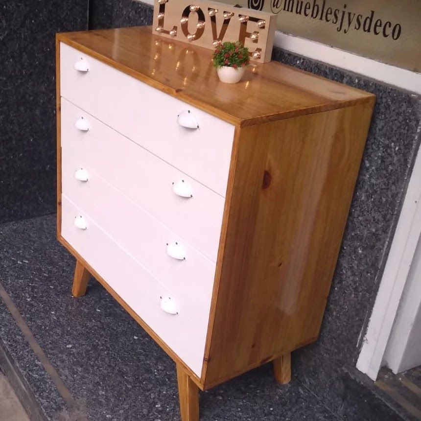 Cómoda de madera con cuatro cajones. Cajones blancos, laterales de madera clara y un letrero de 