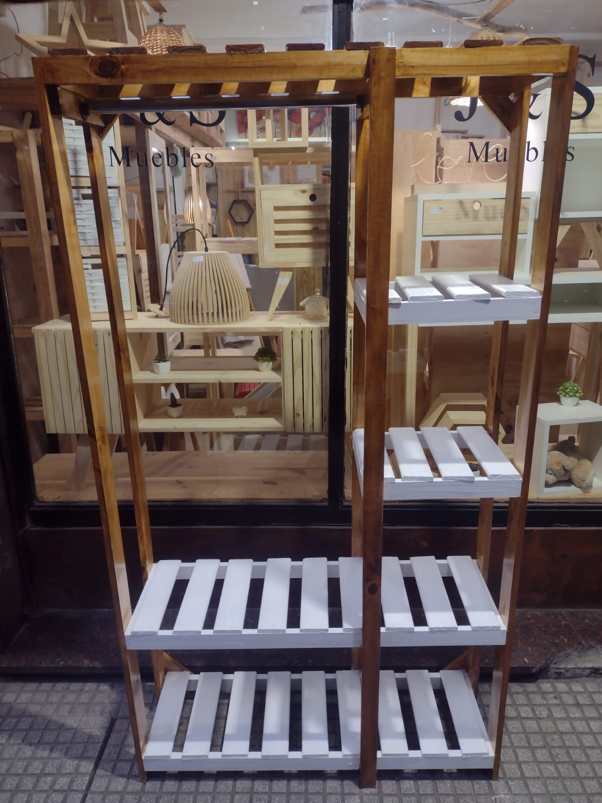 Estantería de madera con estantes de listones blancos en una tienda.