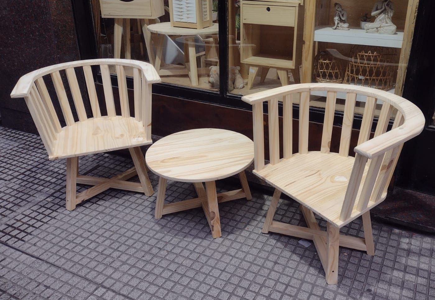 Dos sillas de madera y una pequeña mesa redonda en un patio de ladrillo.