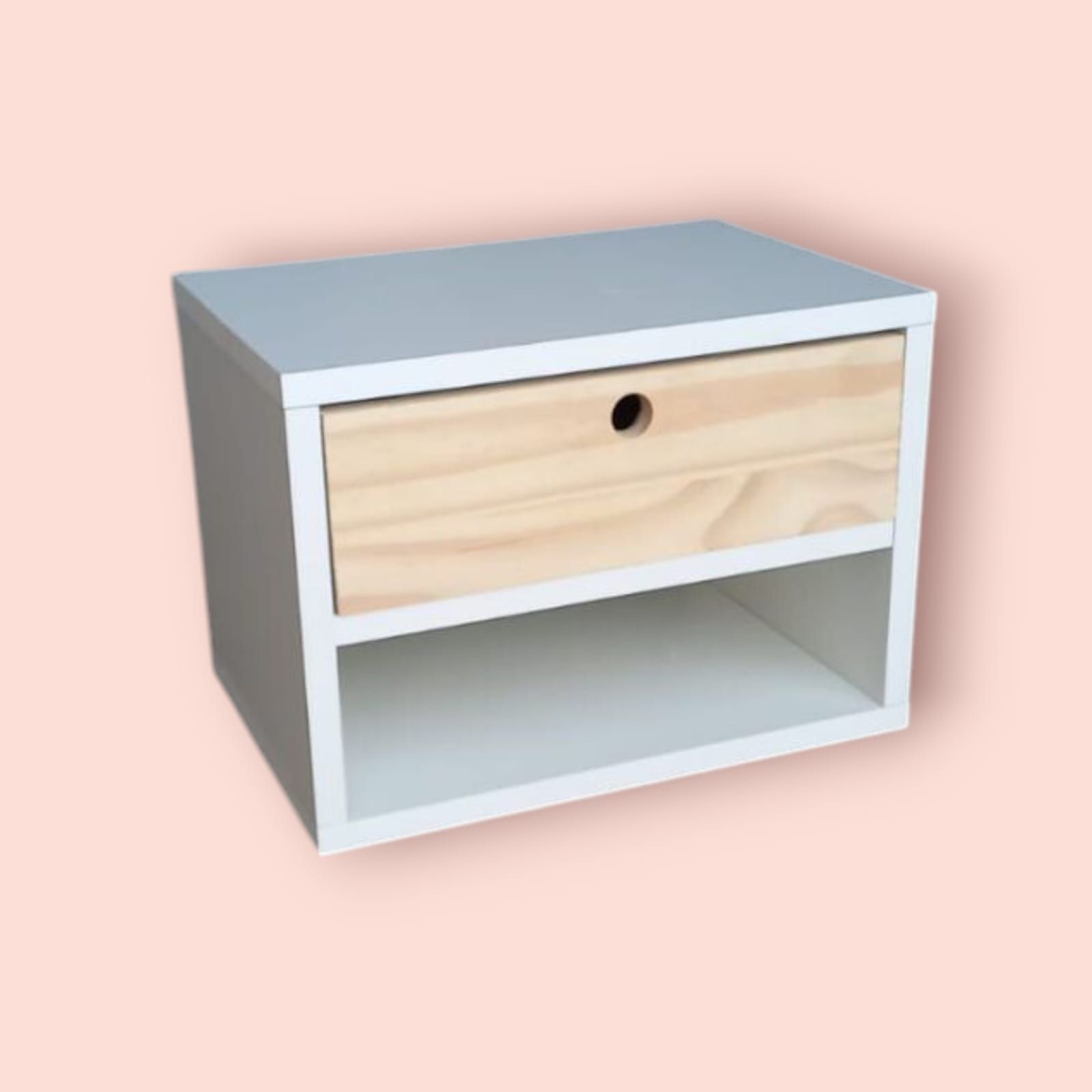 Mesita de noche blanca con cajón y estante de madera sobre fondo rosa.