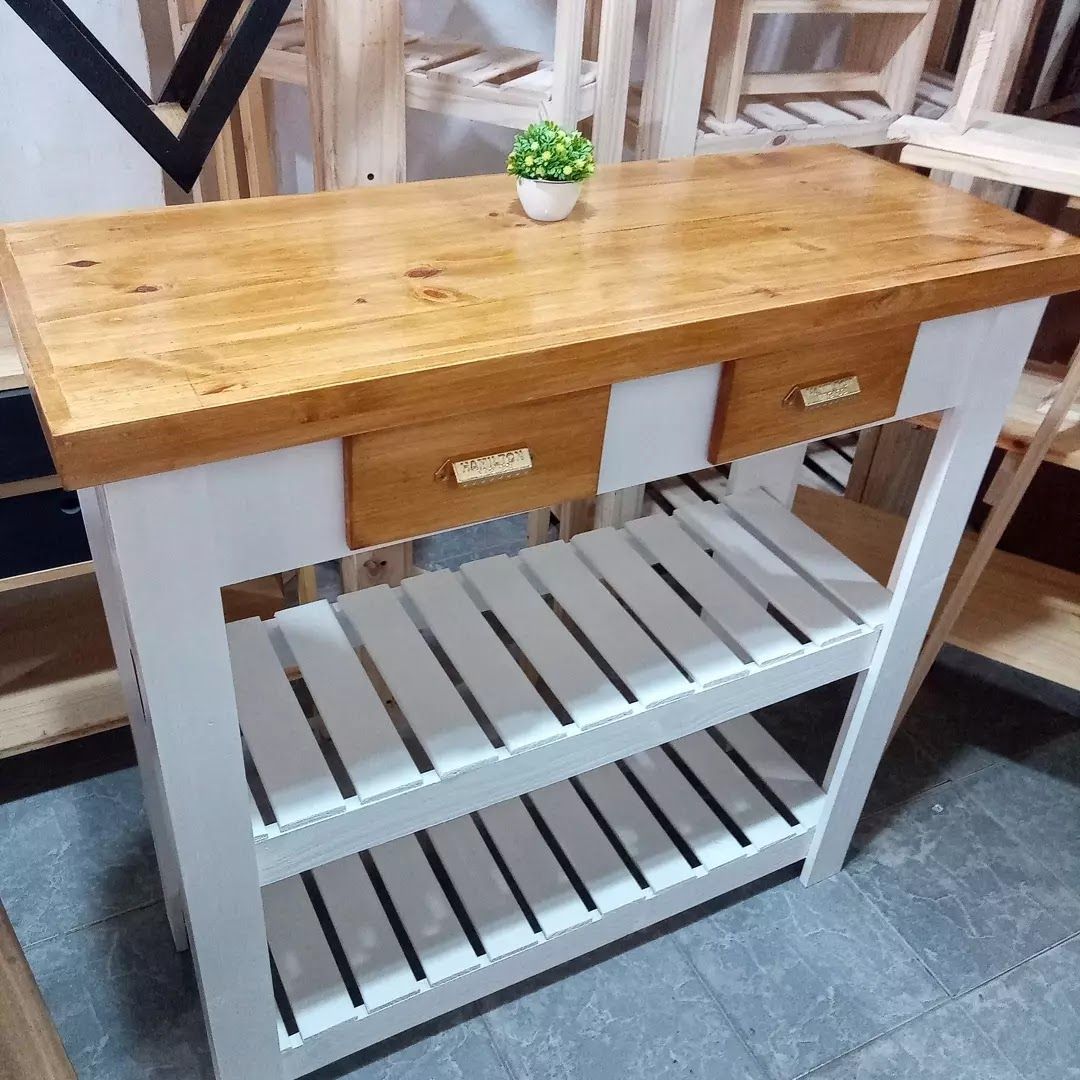 Isla de cocina de madera con estructura blanca, encimera de madera natural, dos cajones y estantes de listones.