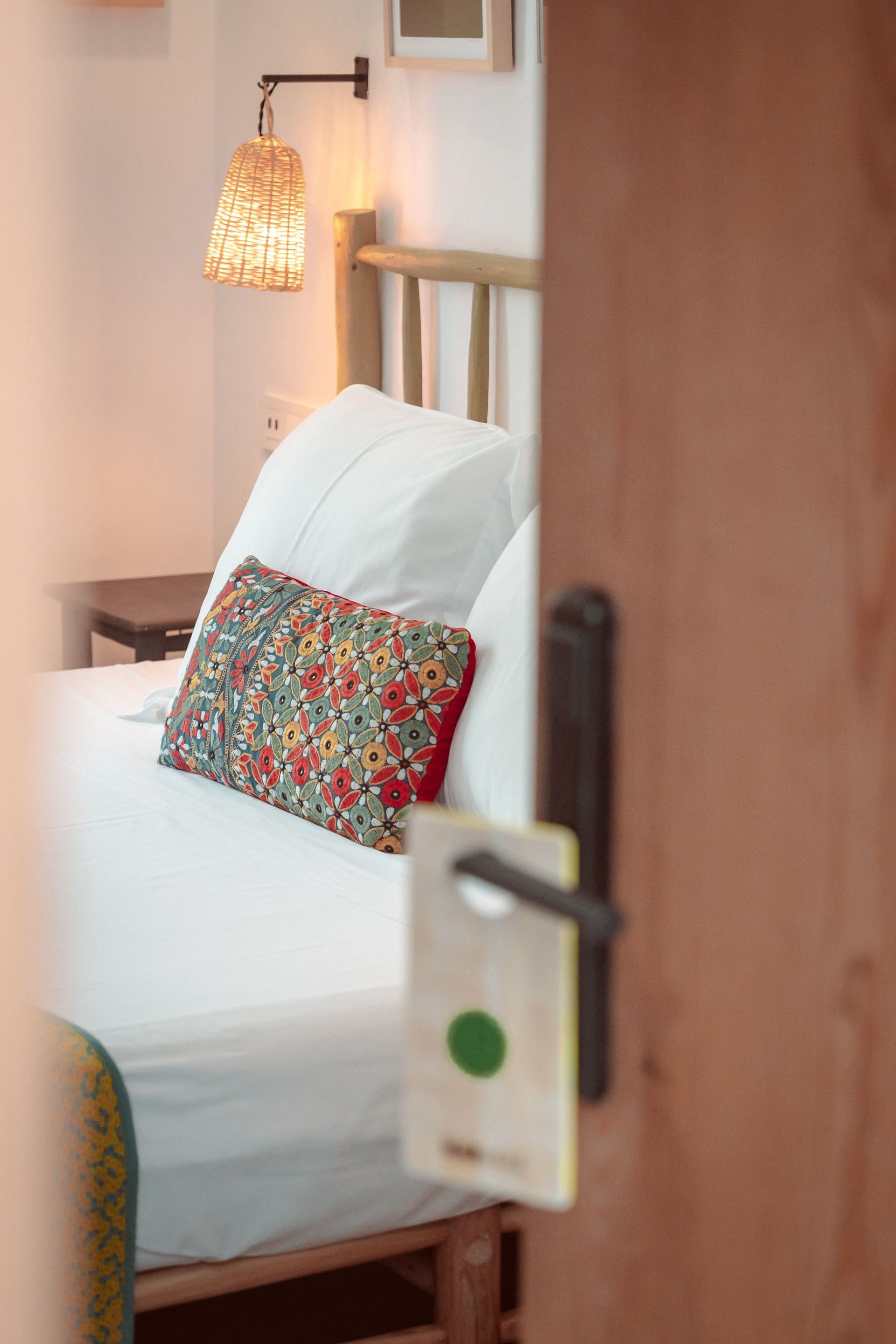 A bedroom with a bed , nightstand , lamp and door.