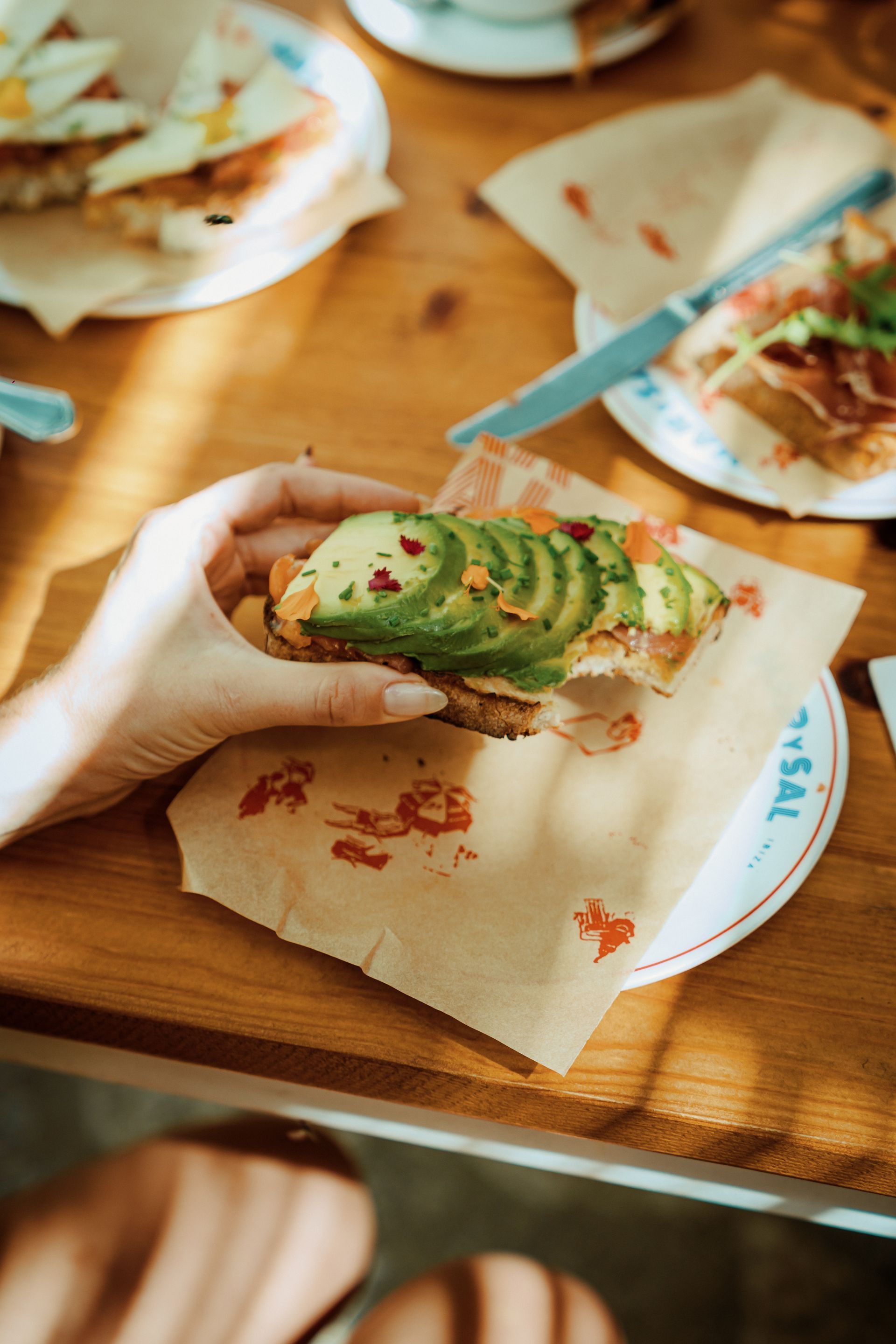A person is eating a sandwich with avocado on it.