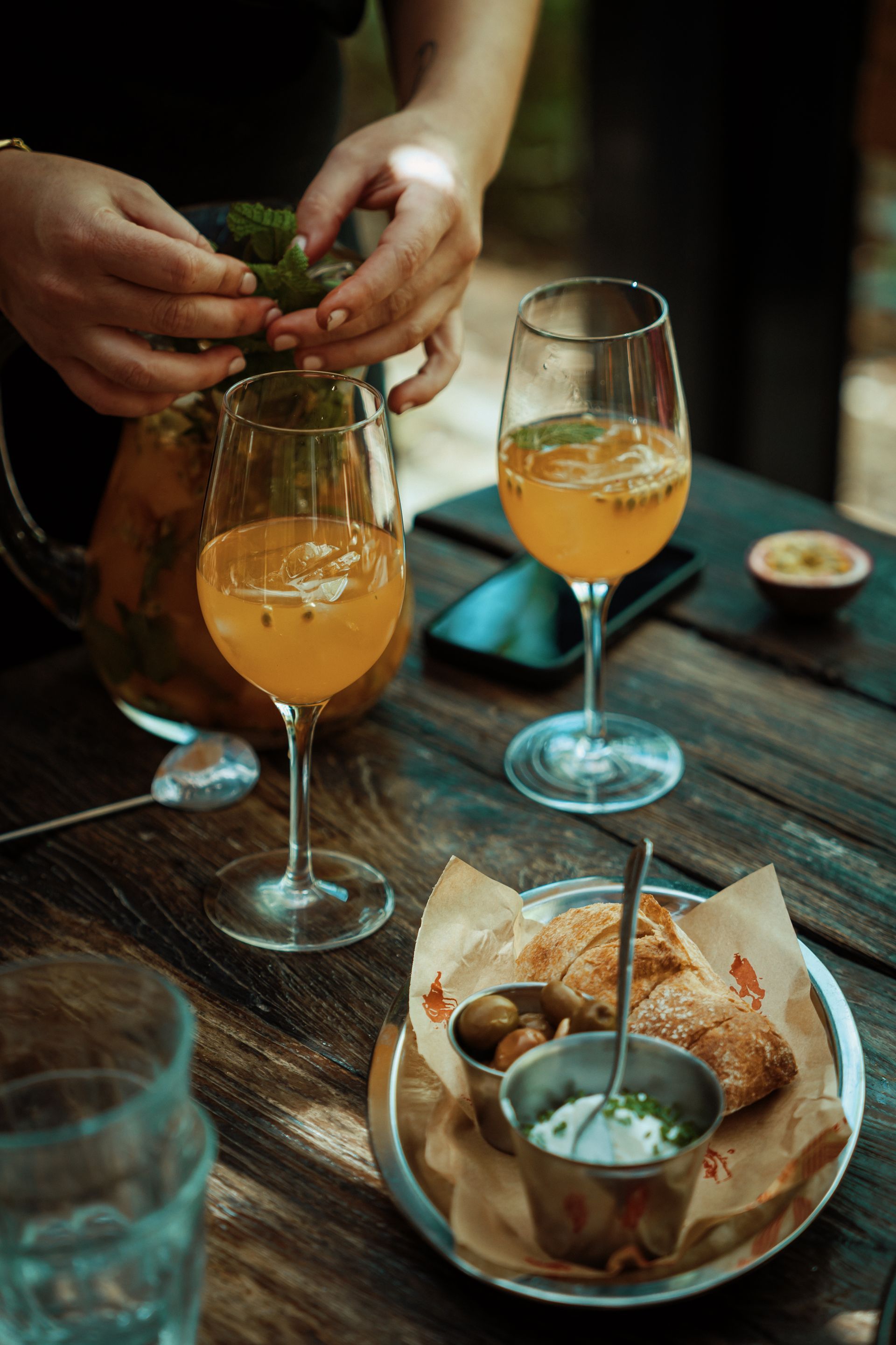 A person is pouring a drink into a glass on a wooden table.