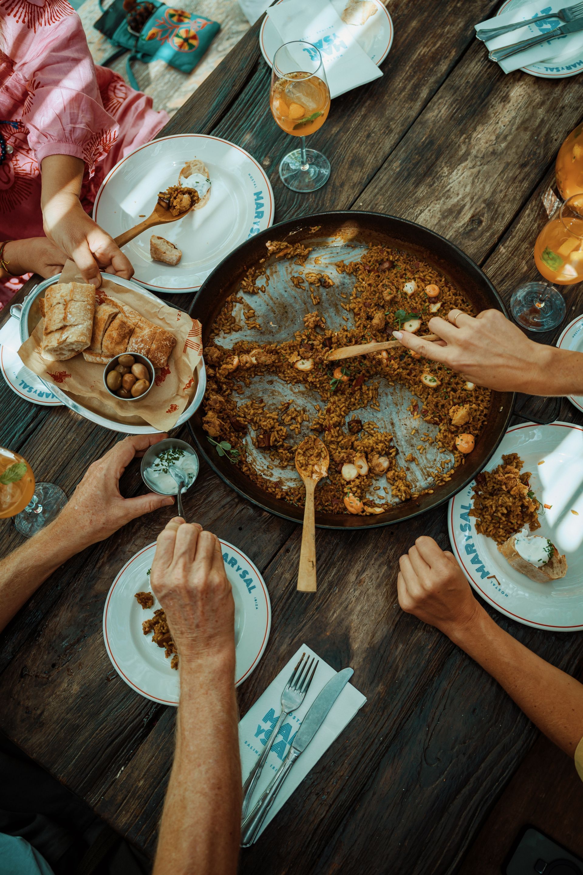 A group of people are sitting at a table eating paella.