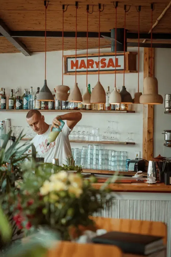 A man is pouring a drink into a glass in a restaurant.