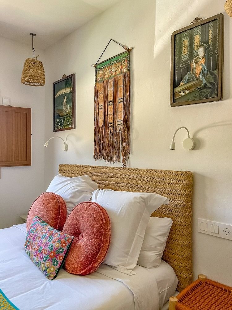 A bedroom with a bed , pillows and paintings on the wall.
