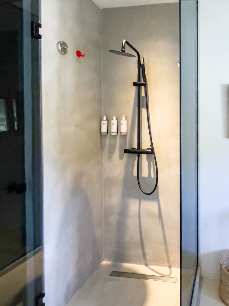 A shower with three bottles of shampoo on the wall