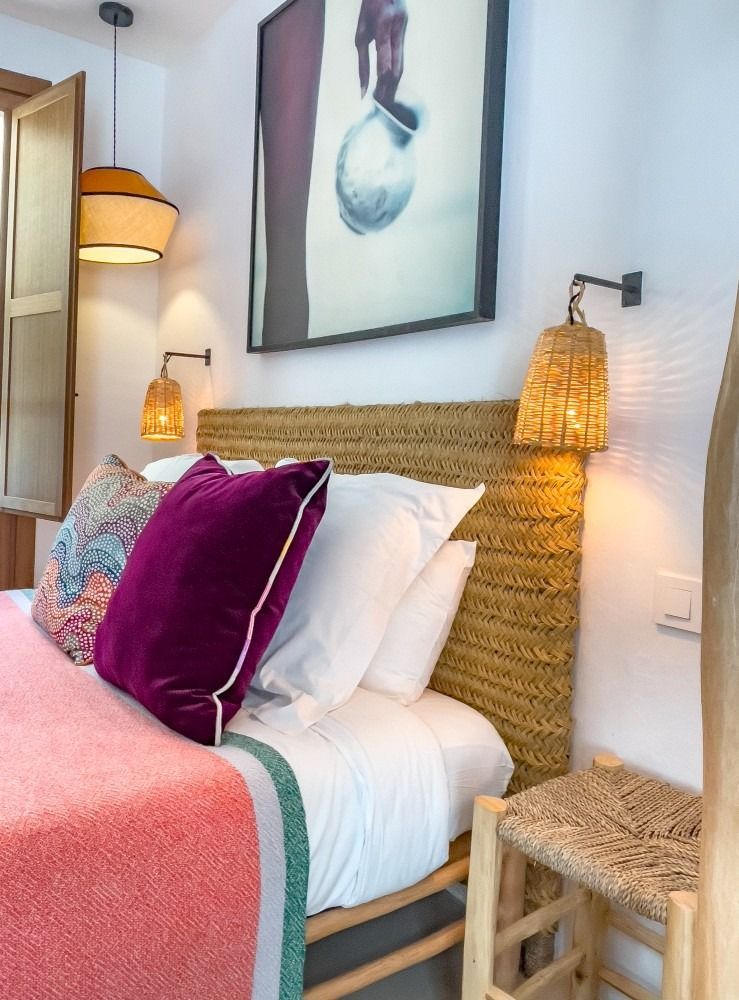 A bedroom with a bed , chair , lamp and a picture on the wall.
