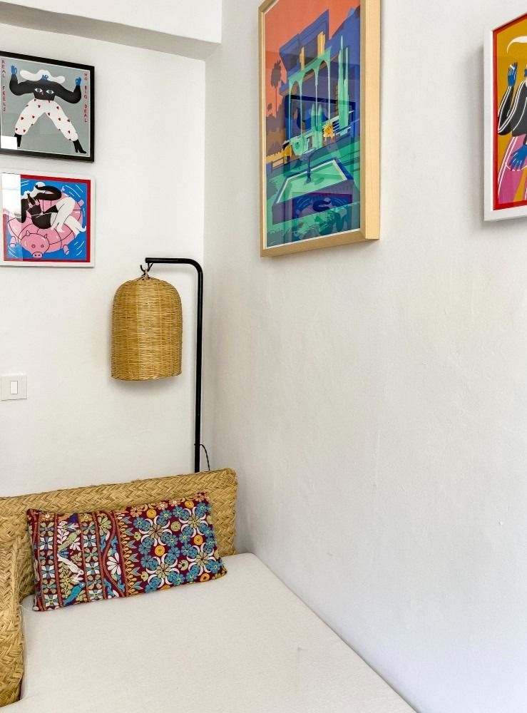 A corner of a room with a bed and paintings on the wall