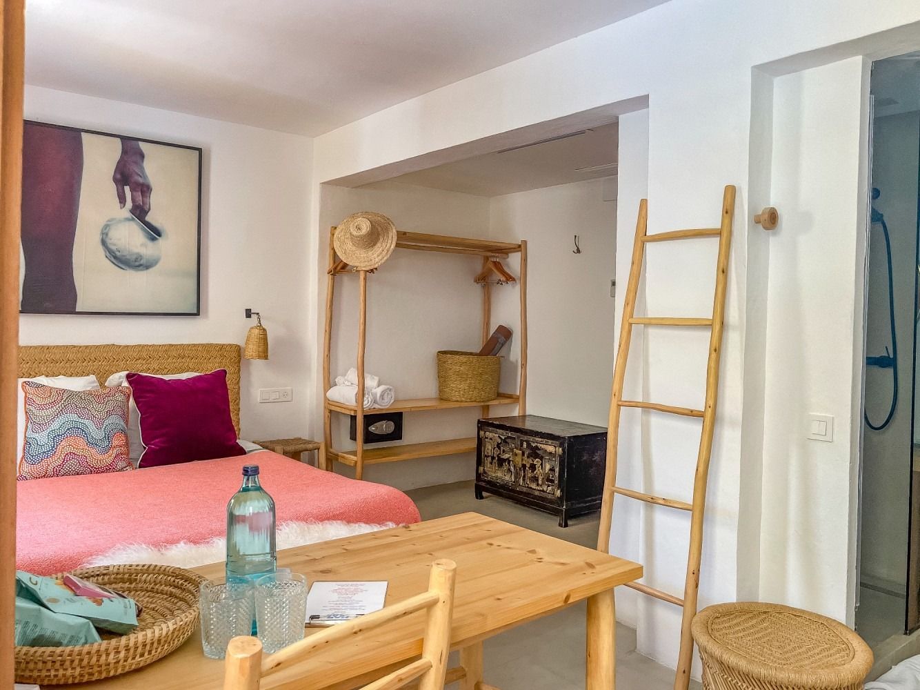 A bedroom with a bed , table , chairs and a ladder.