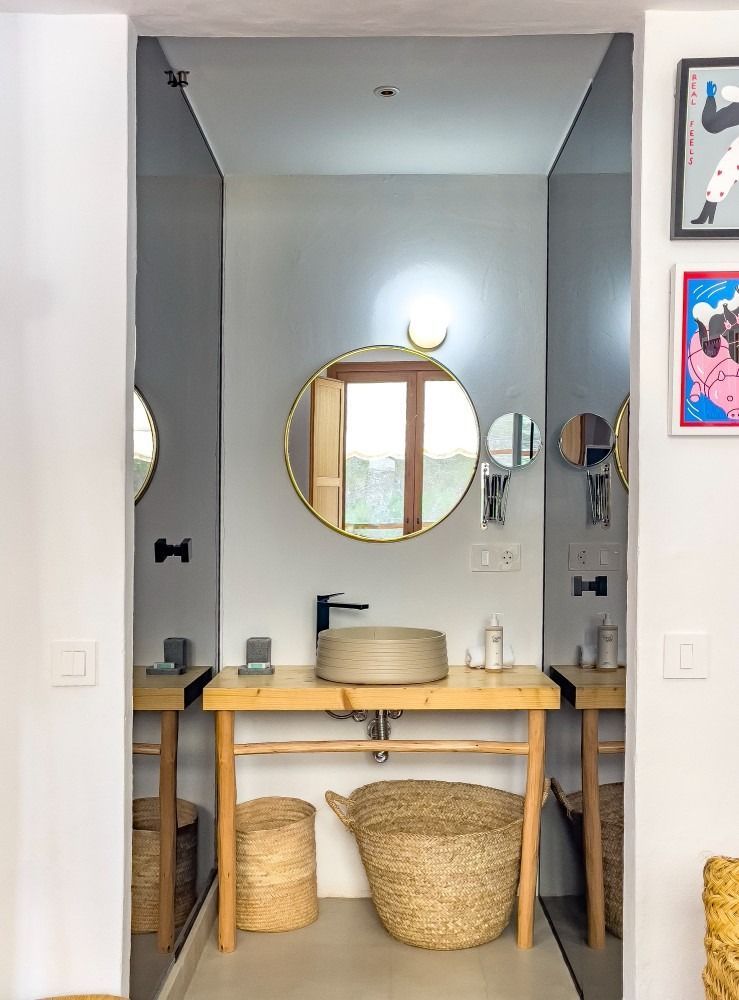 A bathroom with a sink , mirror and wicker baskets.