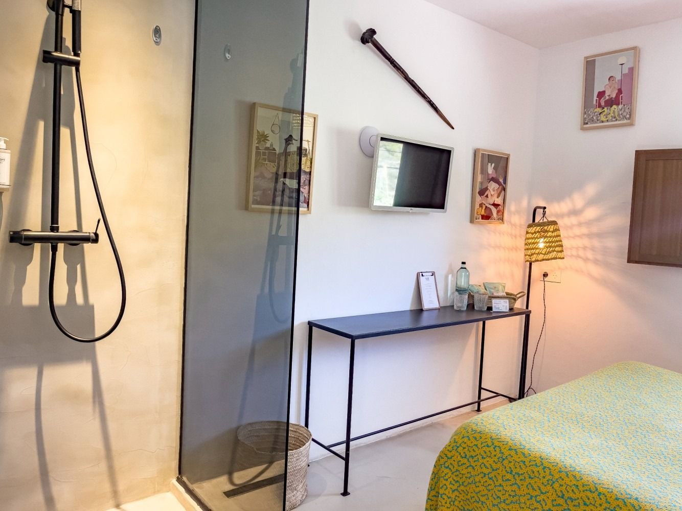A bedroom with a bed , desk , television and shower.