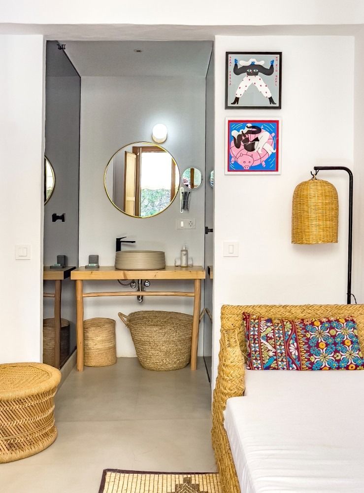 A bathroom with a sink , mirror and wicker furniture.
