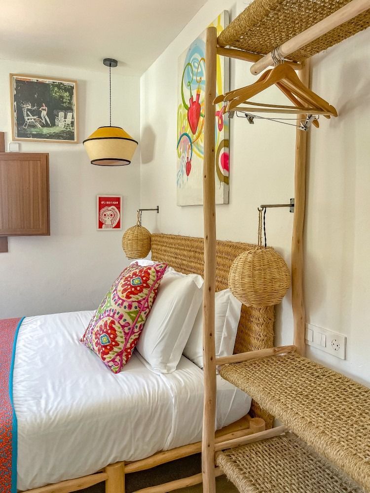 A bedroom with a bed and a wicker shelf.