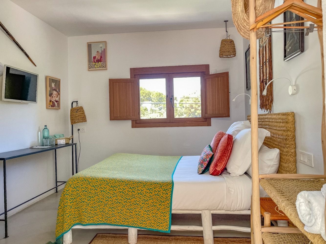 A bedroom with a bed , a table , a television and a window.