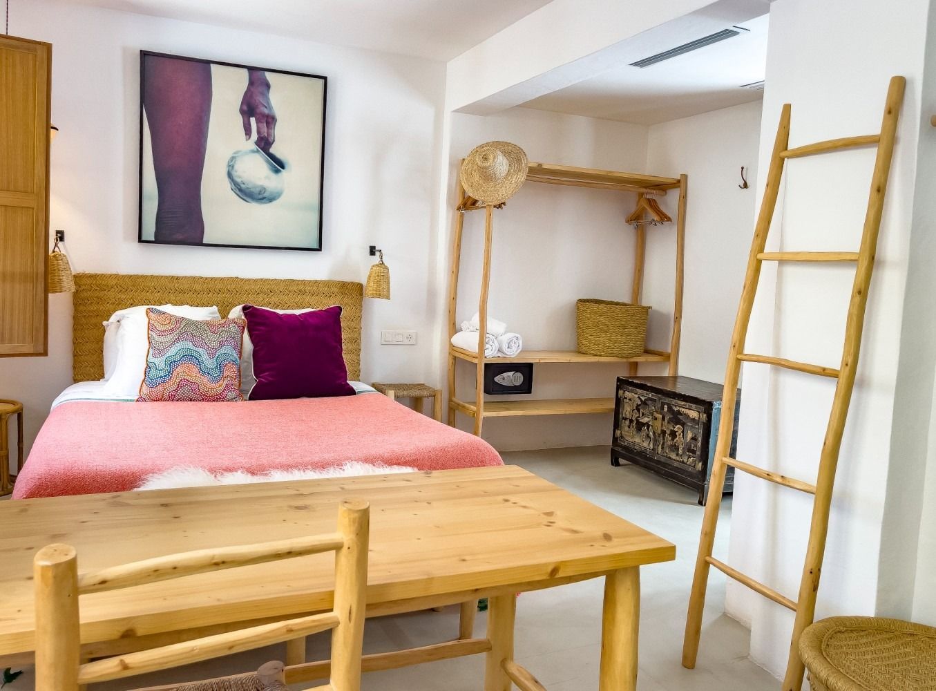 A bedroom with a bed , table , chairs and a ladder.