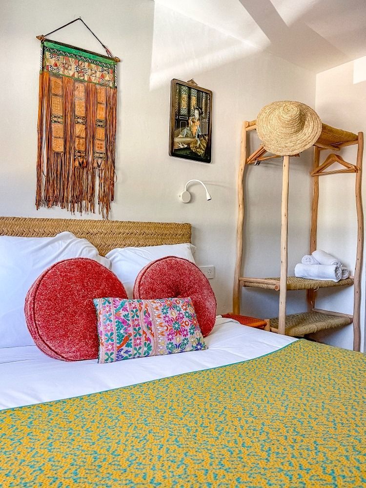 A bedroom with a bed , pillows , a hat and a ladder.