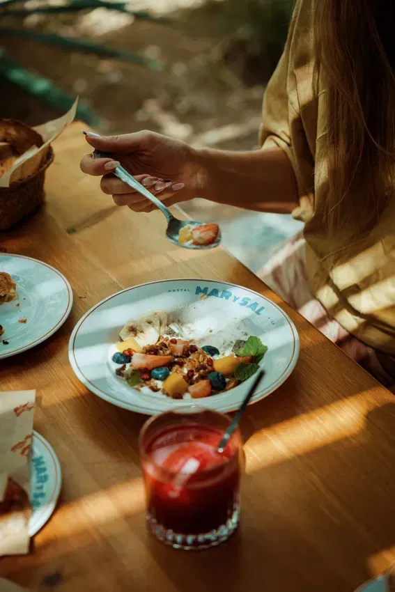 A woman is sitting at a table eating a plate of food.