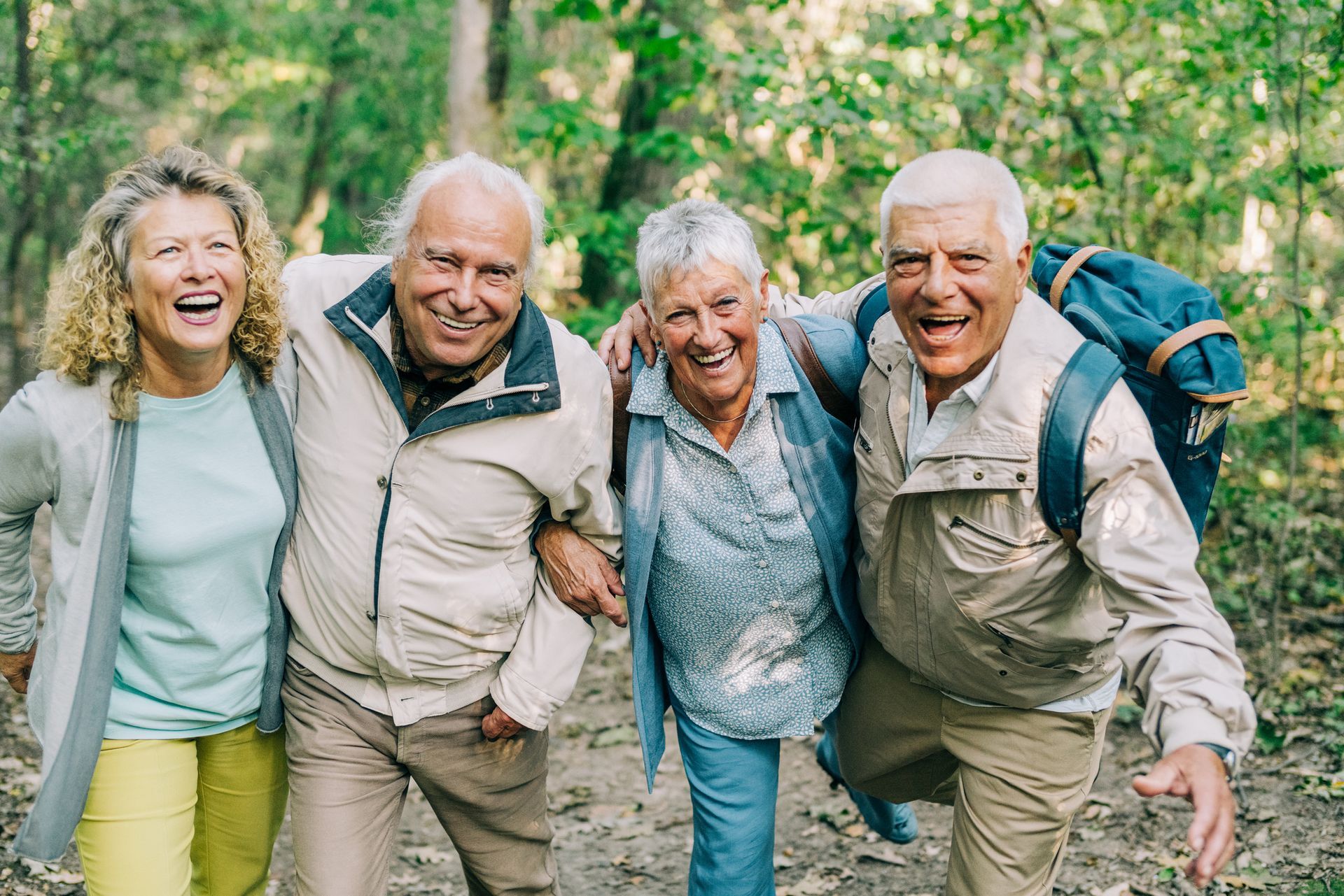 A group of elderly people are standing next to each other in the woods.