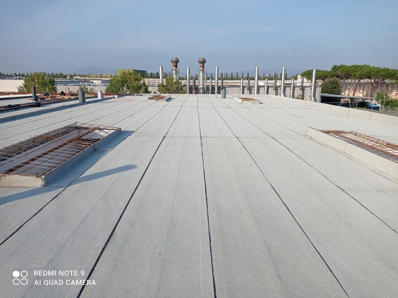 Terrazza sul tetto con ampia superficie bianca, ringhiere e vista sulla città in lontananza.