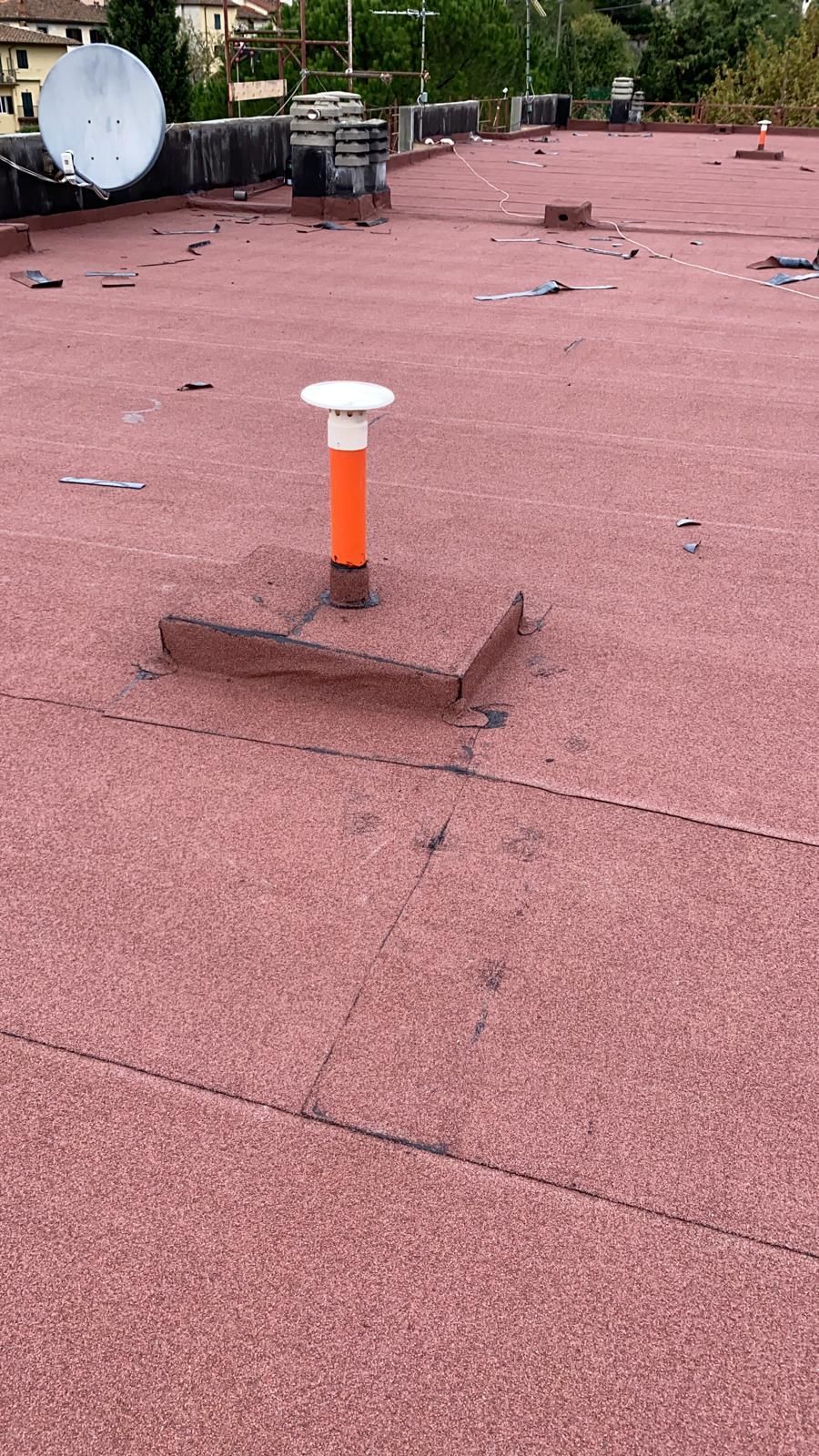 Tetto con un piccolo tubo di ventilazione arancione e un'antenna parabolica sullo sfondo.